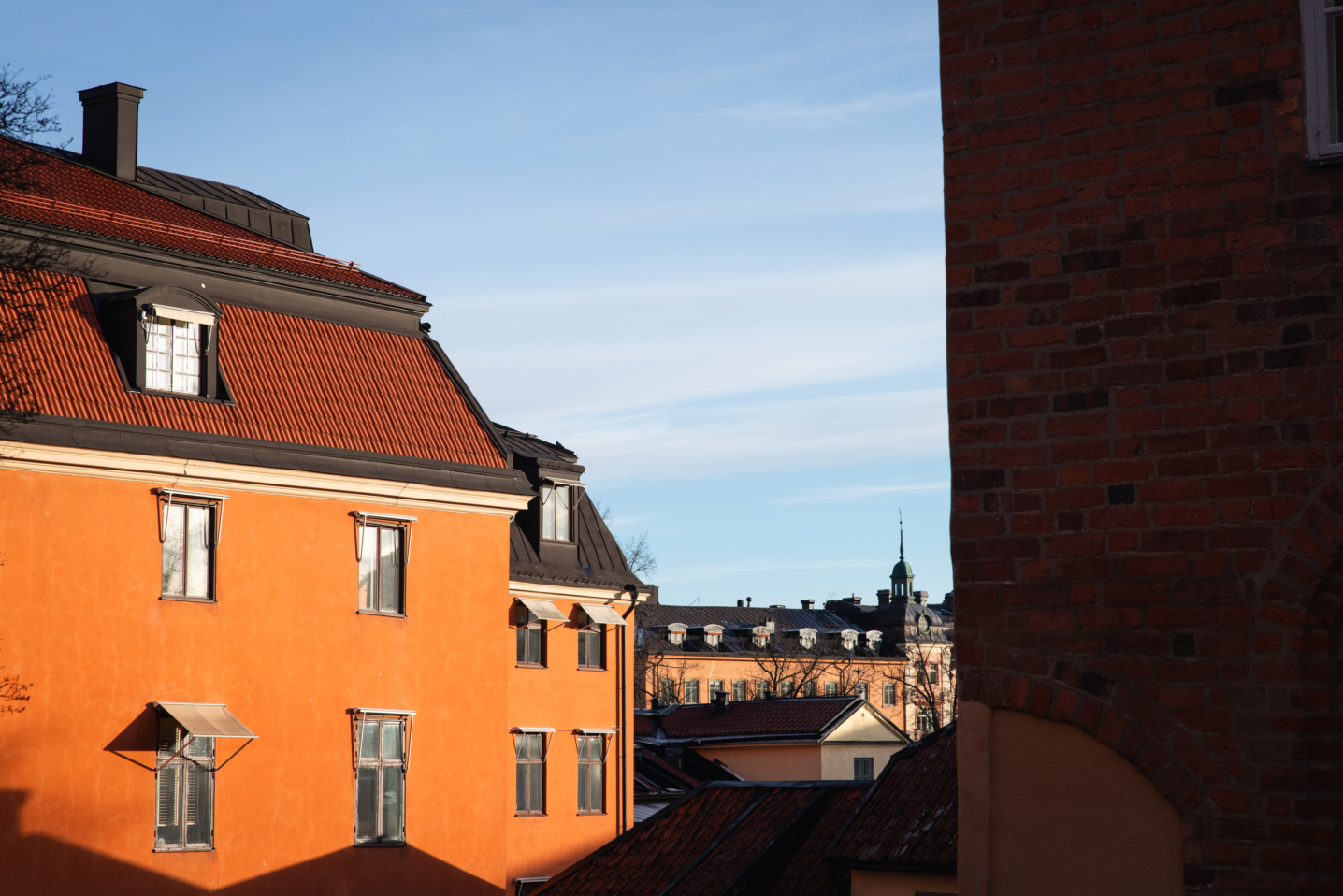 Bild tagen på fasad i roströd fasad i centrala Uppsala med himmel i bakgrunden.