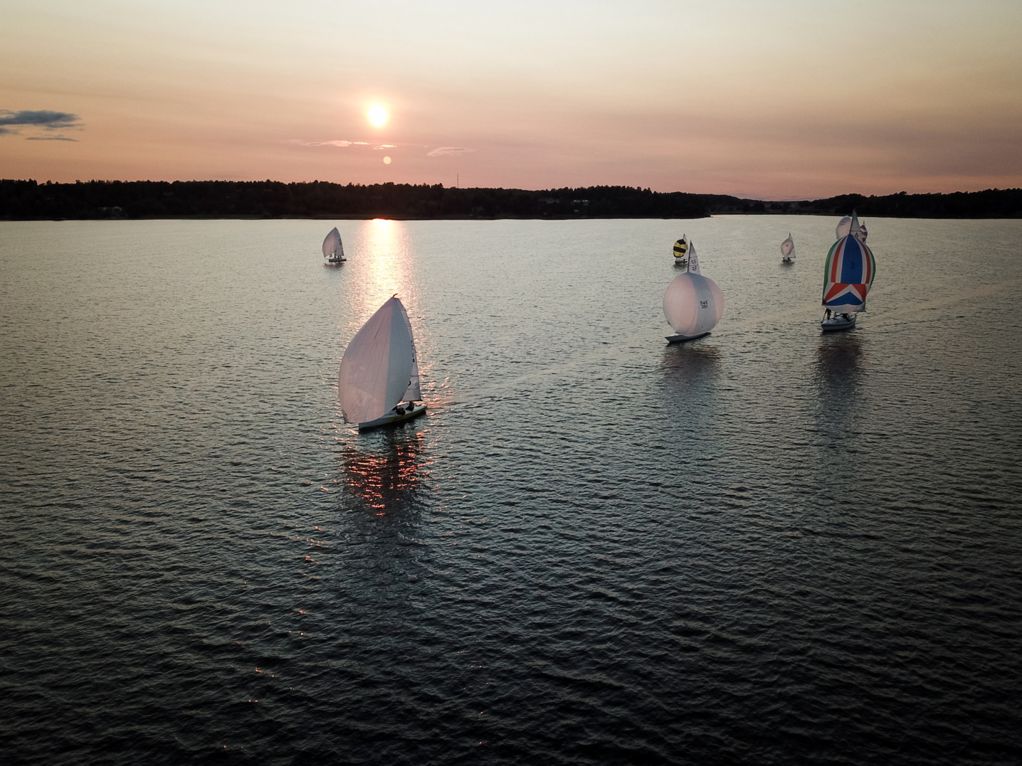 Segelbåtar på hav med horisont i himmel i bakgrund.